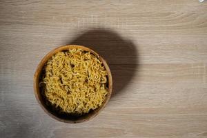 Fried instant noodle on a wooden bowl and wooden table photo
