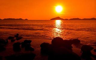 Ocean orange sunset landscape with rocks in silhouette photo