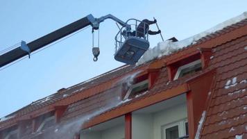 trabalhador na empilhadeira removendo a neve do telhado do prédio, câmera lenta video