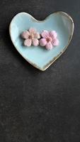 Coconut milk flavor, pastel pink color, Sam Pan Nee traditional Thai handcraft snack on pastel blue heart shape plate, Dark background, vertical image with copy space photo