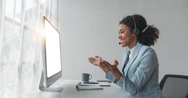 close up call center operator in wireless headset talking with customer, woman in headphones with microphone consulting client on phone in customer support service, looking at computer screen photo