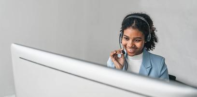 close up call center operator in wireless headset talking with customer, woman in headphones with microphone consulting client on phone in customer support service, looking at computer screen photo