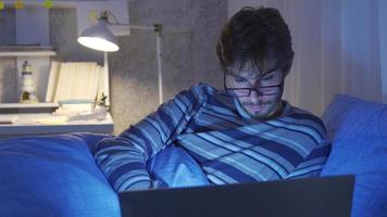 Person falling asleep while looking at laptop in bed. Person working on laptop in bed falls asleep. He looks sleepy and tired. video