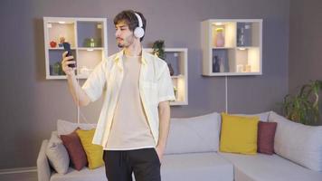 Young man listening to music with headphones on his smartphone. Happy young man in headphones and listens to music from music app and dances. video