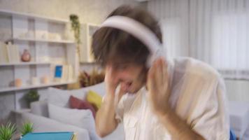 Happy young man dancing at home having fun with funny dance moves. Funny and entertaining young male student listening to music while studying at home. video