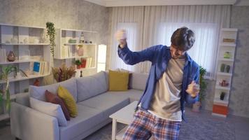 alegre bailarín teniendo divertido en el salón a hogar bailando solo. joven hombre bailando solo en moderno casa y teniendo divertido me gusta loco. movimiento cámara imágenes. video