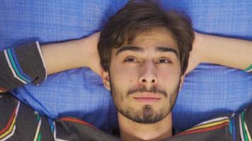 To live is a hope.  Happy life. Close-up portrait of young man lying in bed daydreaming. video