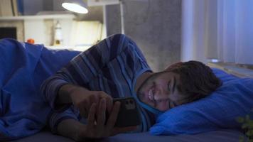 Messaging on. Young man texting on the phone. The young man texting on the phone at night is happy. video