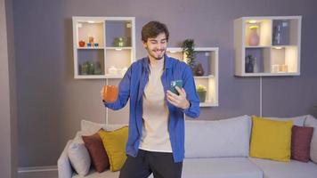 Young male student or teenager listening to music and dancing at home. Happy Young man listening to music and dancing while drinking coffee in the morning. video