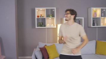 Cheerful young man is dancing at home. Funny young man in glasses dancing alone at home. video