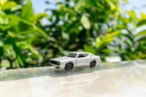 Bogor, Indonesia, March 18th, 2023 - Concept for nature and adventure with your car. Toy of old Nissan Skyline 2000 GT-R placed at the edge of glass rooftop, after some edits. photo