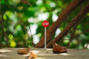 A photo of a stop sign miniature with branch and leaves background, after some edits.