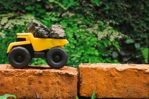 después algunos ediciones, un foto de un amarillo juguete tugurio camión tratar a llevar pila de piedras en un ladrillo.