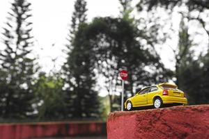 A yellow toy car meets a stop sign in the park. photo