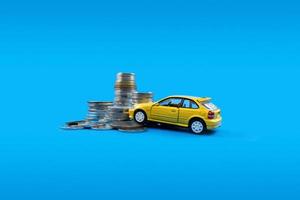 A yellow toy car and pile of coins. Concept of financial planning for buying a car. photo