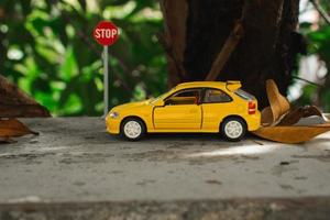 un foto de un amarillo juguete coche Satisface un detener firmar, después algunos ediciones