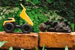 después algunos ediciones, un foto de un amarillo juguete tugurio camión tratar a llevar pila de piedras en un ladrillo.