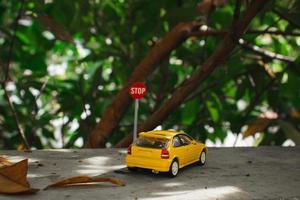 A photo of a yellow toy car meets a stop sign, after some edits.