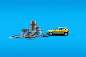 A yellow toy car and pile of coins. Concept of financial planning for buying a car. photo