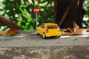 A photo of a yellow toy car meets a stop sign, after some edits.