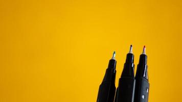 A row of pens with a yellow background photo