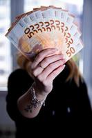 mujer mano participación un ventilador de euro billetes en un negro antecedentes foto