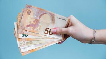 Woman's hand holding fifty euro banknotes on a blue background. photo