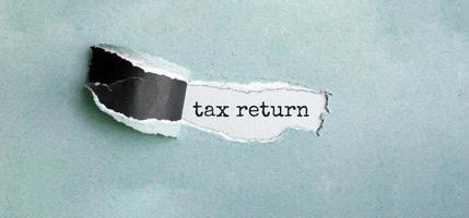 The text tax return appearing behind torn green paper photo