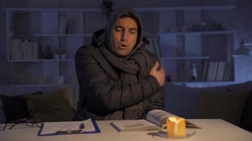 The man who is cold at home. Natural gas outage.  Man trying to warm up by candlelight. video