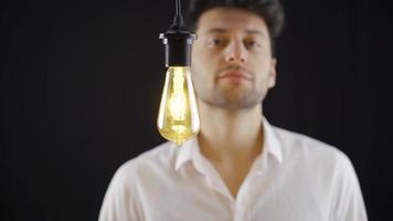 creativo inteligente hombre encuentra nuevo ideas simbólico idea lámpara luces arriba. pensativo hombre viene arriba con un idea y toques un simbólico lámpara y luces arriba. idea lámpara. video