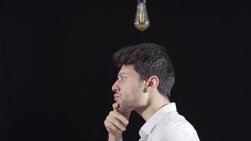 Thoughtful man gets an idea, a symbolic lamp lights up above his head. When the man comes up with an idea, the bulb goes on above his head. Brainstorming. video