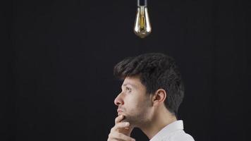 Young Man With An Idea. A light bulb is burning above his head. The wise man comes up with an idea, a symbolic lamp lights up above his head. video