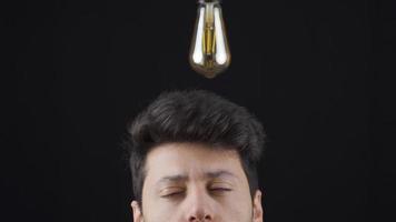 un lámpara luces arriba encima el cabeza de el hombre quien tiene un idea. a generar ideas inteligente hombre viene arriba con un idea, un simbólico idea lámpara luces arriba encima su cabeza. video