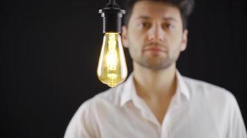 un inteligente hombre viene arriba con un idea y toques un simbólico lámpara y luces él. pensativo hombre viene arriba con un idea y toques un simbólico lámpara y luces arriba. idea lámpara. video