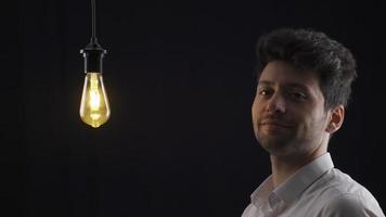 Smart man comes up with a new idea and turns it on by touching the light bulb with his finger. The man touches the lamp with his finger and the lamp lights up, it means he has an idea. video