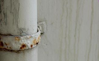 View of rusty and dirty metal water pipes connect to cement  wall photo