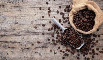 Background of dark roasted coffee beans with scoops setup on wooden background with copy space. photo