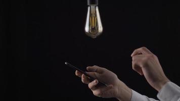 per creare idee. eureka. maschio mano guardare a il Telefono trova un' nuovo idea, invenzione, soluzione e il lampada giri Su. video