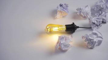 inspiration och kreativ aning begrepp. en bra aning. gul ljus Glödlampa står bland skrynkliga papper som en symbol av ny aning. video