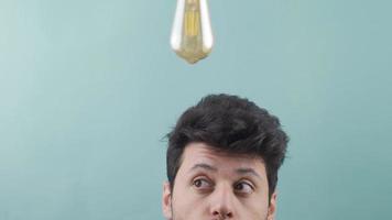 The bulb lights up above the man's head when he gets an idea. Thoughtful businessman has an idea, a symbolic idea lamp lights up above his head. video