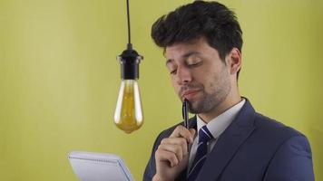 Businessman taking notes generates a new idea. Idea lamp. The idea lamp of the businessman who finds a new idea lights up. Eureka. video