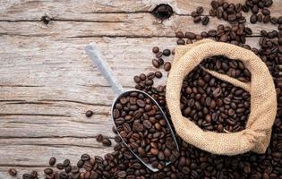 Background of dark roasted coffee beans with scoops setup on wooden background with copy space. photo