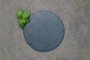 Empty pizza platter for homemade baking set up on dark concrete. Food recipe concept on dark stone background texture with copy space. photo