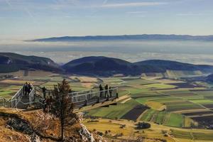 view to a skywalk and a wide green valley with fog photo