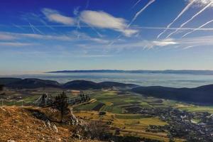 view to a skywalk and wide green valley with fog and blue sky photo