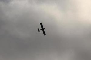 pequeño avión volador en el cielo en contra oscuro nubes foto