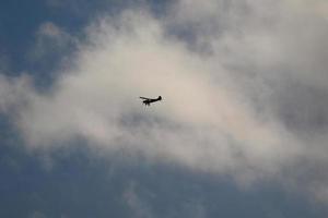 pequeño avión volador en el cielo en contra oscuro nubes foto