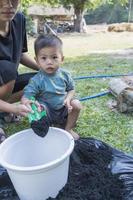 Toddler son and mother teaching little son preparing the soil to plant in a garden, mother and son relationship. Mommy's little helper. Gardening. Leisure activities family concept photo