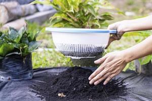 preparación de una mezcla de suelo a partir de compost fértil, humus y vermiculita en el suelo de una bolsa de basura negra en el jardín. mezclar los componentes del suelo para la preparación del sustrato para trasplantar plantas. foto