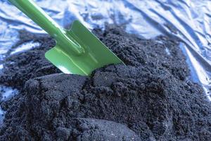 Preparation of soil mixture from fertile compost, humus and vermiculite on  black garbage bag floor in garden. Mixing the soil components for the preparation of the substrate for transplanting plants. photo